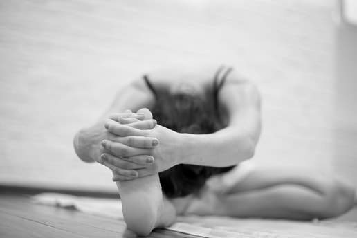 Woman sitting in yoga position on hardwood floor in yoga studio